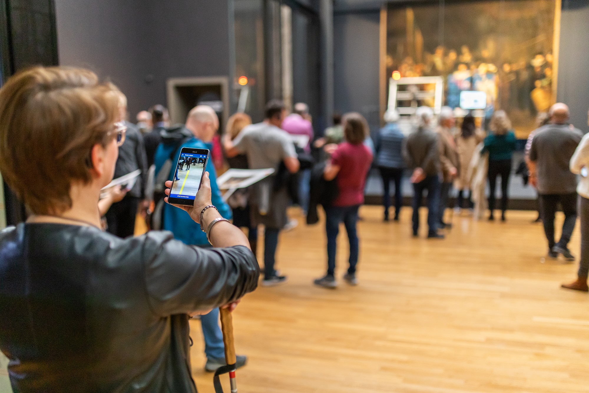 Vrouw met taststok gebruikt smartphone als hulpmiddel in museum