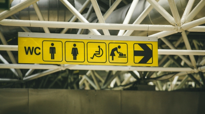 Routebord met gele pictogrammen voor toilet voor dames, heren en mindervaliden