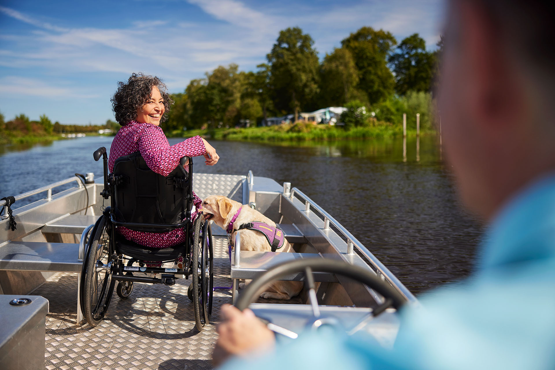 Een mevrouw in een rolstoel zit op een boot en kijkt naar achter.