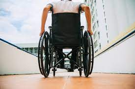 Een rolstoel rijdt over een pad naast een flat.