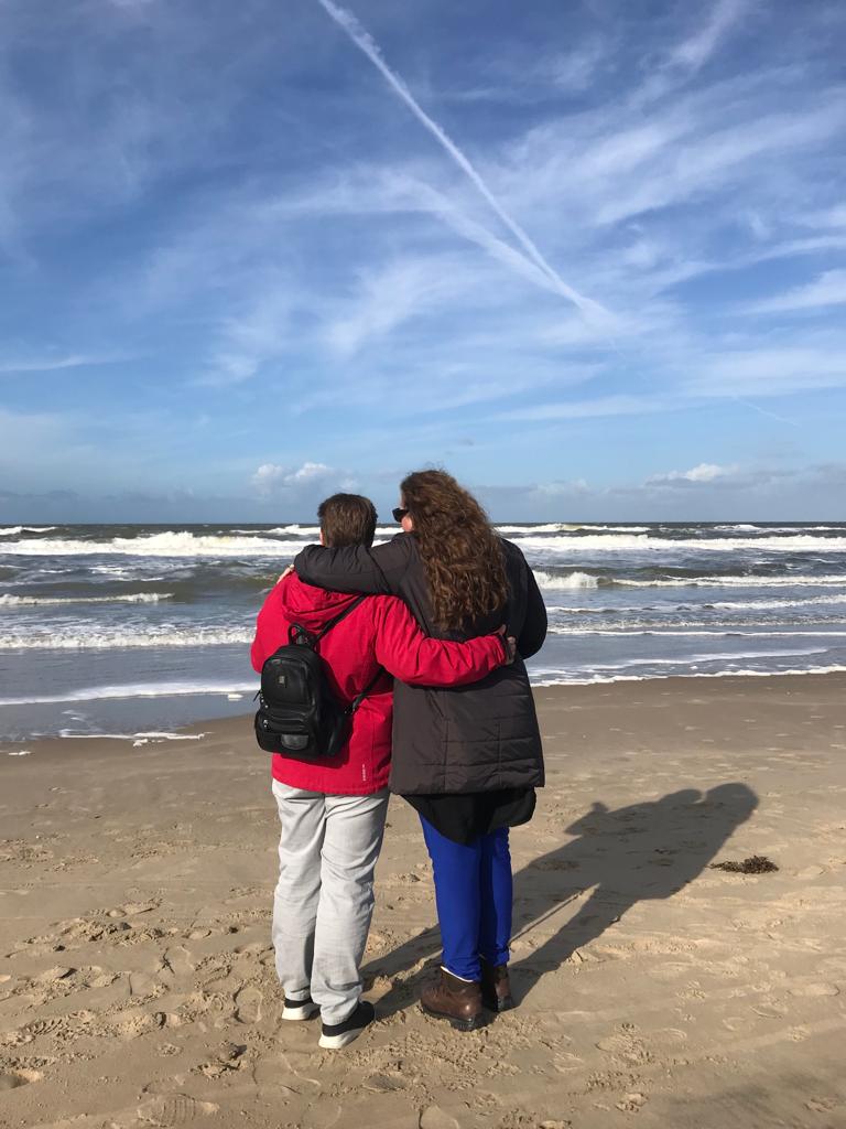 2 mensen kijken naar de zee en staan op het strand.
